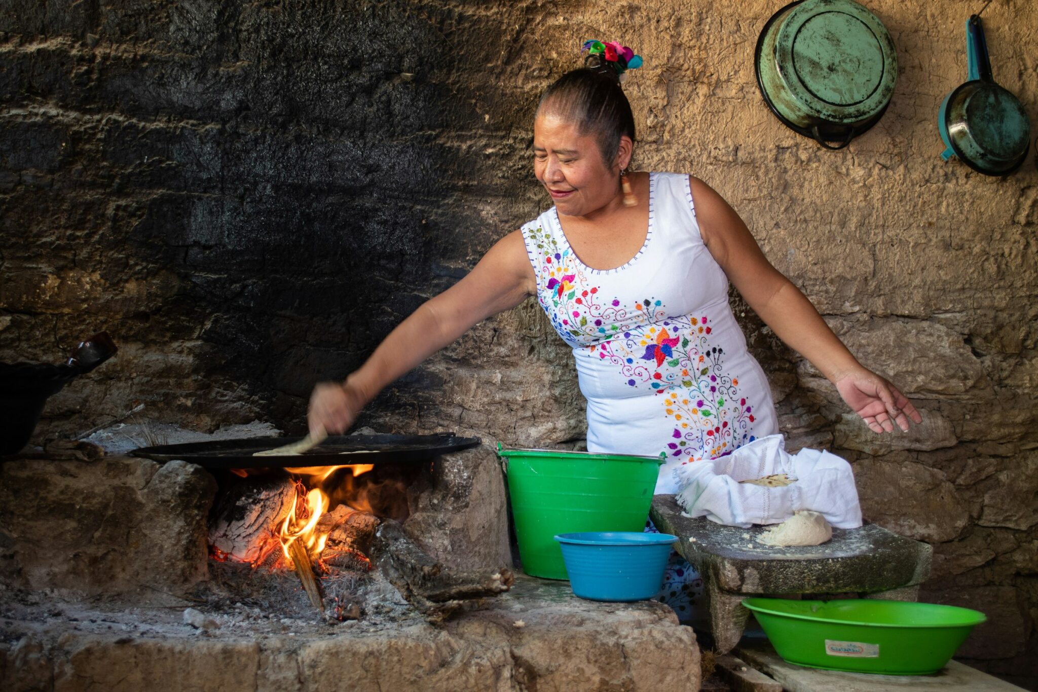 A woman cooking over a wood fire in an outdoor kitchen in Axaxacualco, Guerrero.