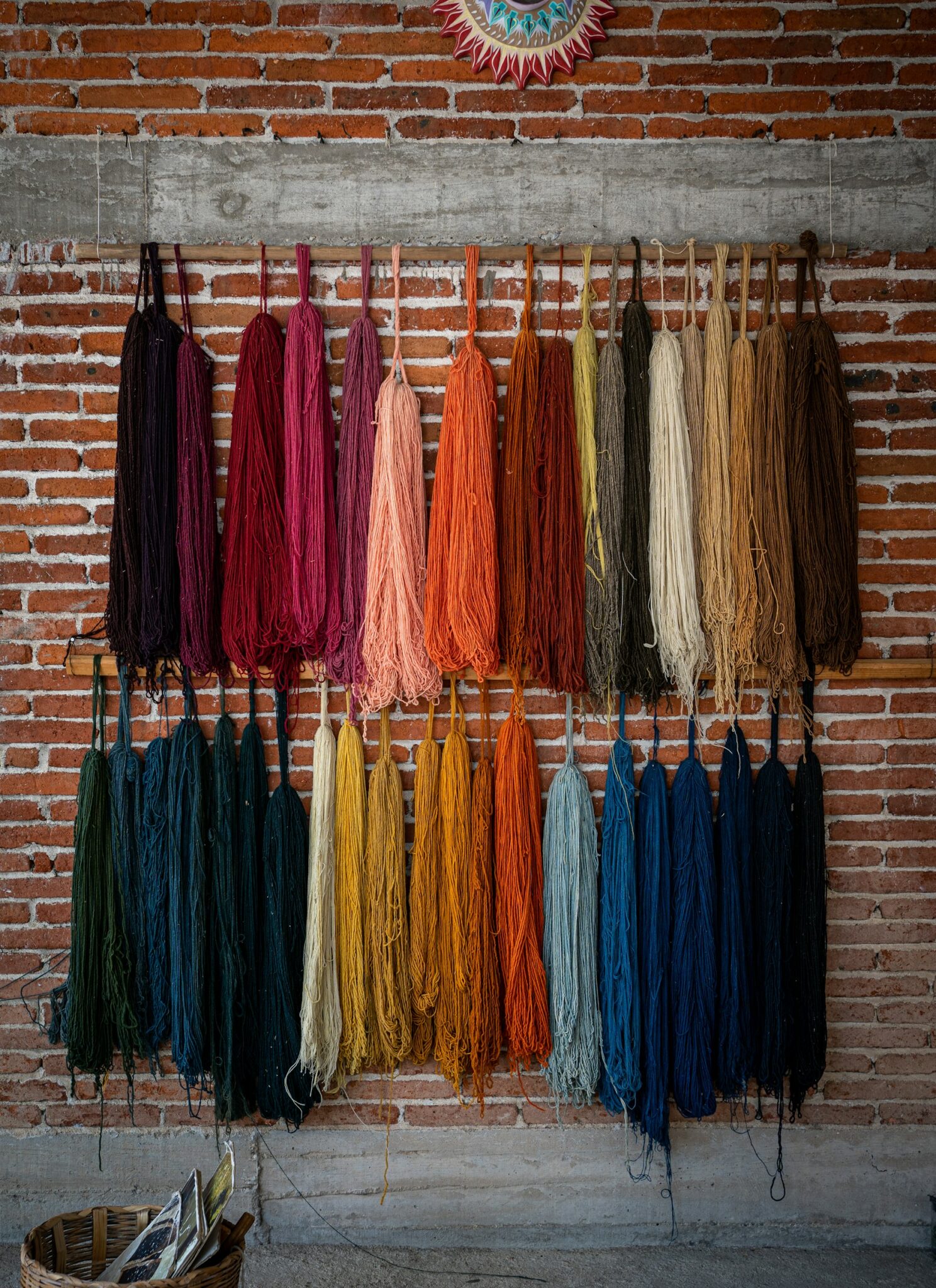 Skeins of naturally coloured wool hanging against a brick wall in Oaxaca.